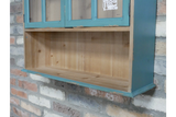 Parisienne wall unit in natural wood and distressed teal paint, close-up angled view against brick wall background.