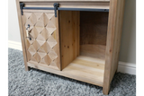 Rustic wooden cabinet with sliding door featuring geometric panel design, open shelf, and metal handle, on gray carpet.