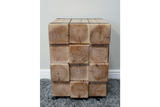 Chunky bedside cabinet made of natural wood blocks showing grain and cracks, front view on gray carpet.