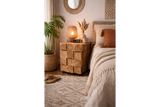 Chunky bedside cabinet made of natural wood blocks with visible rings, shown at a bedroom corner with decorative items on