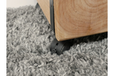 Close-up of light wood chunky bedside cabinet corner with black caster wheel on gray shag carpet