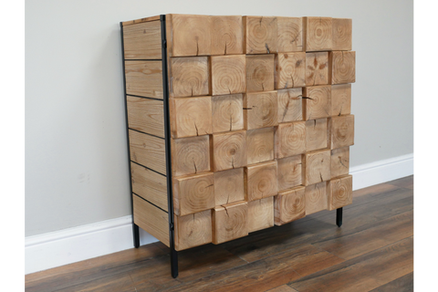 Wooden chunky cabinet with front made of large square wood blocks, black metal frame, standing on wooden floor.