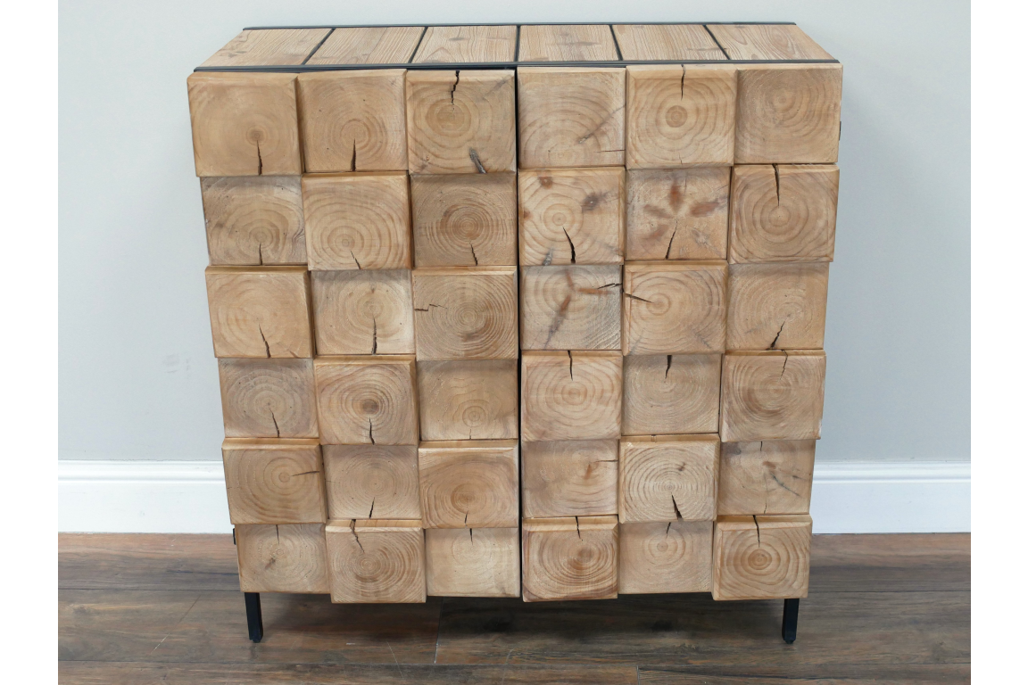 Chunky wooden cabinet with natural wood blocks front and black metal legs, shown from the front against a gray wall.