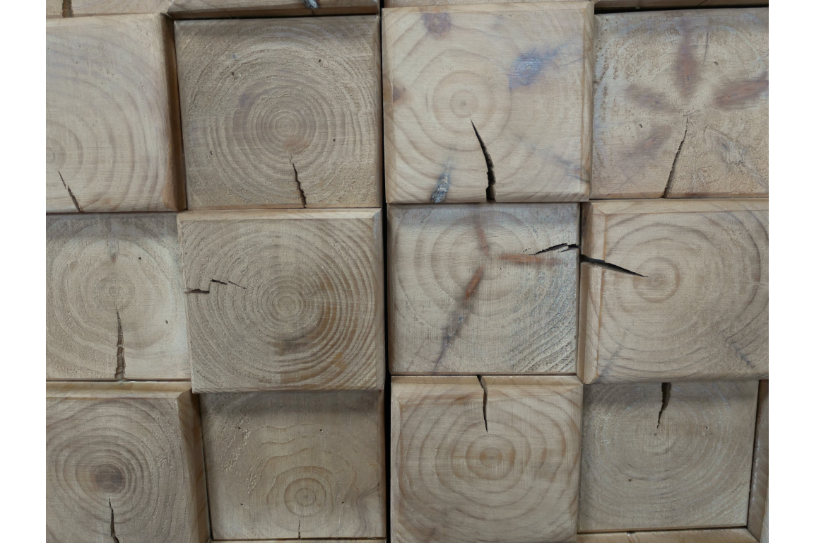 Close-up view of chunky cabinet showing light natural wood blocks with visible grain patterns and cracks.