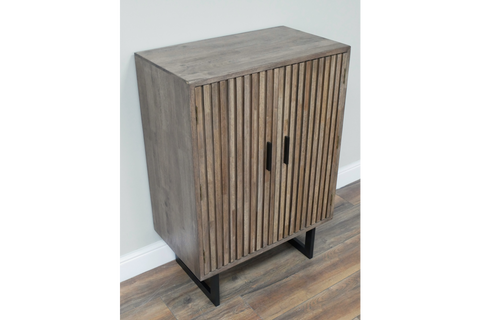 Wooden 2 door slatted cabinet in grey finish with black metal legs, shown at an angle on wood flooring.
