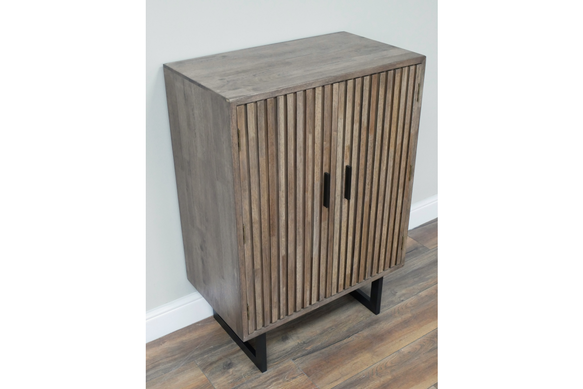 Wooden 2 door slatted cabinet in grey finish with black metal legs, shown at an angle on wood flooring.