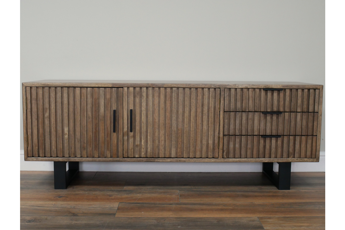 Low wooden TV sideboard with vertical slatted doors and drawers, black handles, black metal legs, front view.