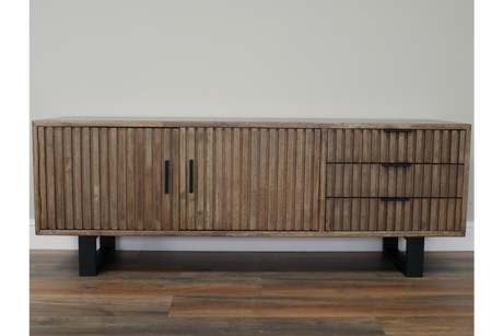 Low wooden TV sideboard with vertical slatted doors and drawers, black handles, black metal legs, front view.
