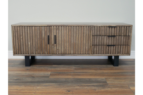 Low wooden slatted TV sideboard with black metal legs, two doors and three drawers, front view on wooden floor.