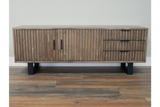 Low wooden slatted TV sideboard with black metal legs, two doors and three drawers, front view on wooden floor.