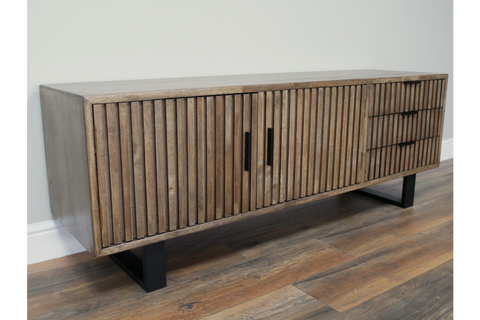 Wooden TV low sideboard with slatted cabinet doors and drawers, black metal legs, angled view on wooden floor