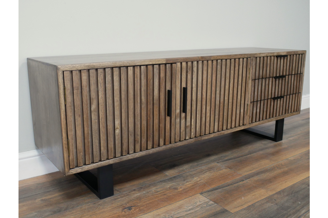 Wooden TV low sideboard with slatted cabinet doors and drawers, black metal legs, angled view on wooden floor