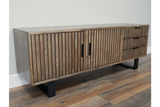 Wooden TV low sideboard with slatted cabinet doors and drawers, black metal legs, angled view on wooden floor
