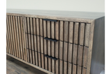 Wooden TV low sideboard with slatted door and drawers, black handles, angled view on light-colored floor.