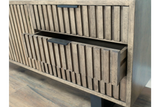 Wooden TV low sideboard slatted cabinet in light brown with black handle, open drawer detail, angled view.