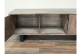 Wooden low sideboard slatted cabinet with open doors showing two interior compartments, black legs, on wooden floor.