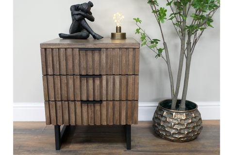 Slatted bedside cabinet in brown wood with three drawers, black handles, black legs, styled with sculpture and lamp top