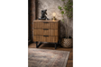 Wooden slatted bedside cabinet with three drawers and black metal legs, shown at an angle in a rustic room setting.