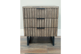 Slatted wooden bedside cabinet with three drawers, black metal handles and legs, front view on wooden floor.