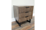 Slatted bedside cabinet in brown wood with three drawers, black metal handles and legs, angled view on wooden floor.
