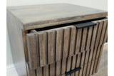 Slatted bedside cabinet in natural wood finish with two drawers, angled view showing texture and black handles.