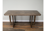 Rectangular wooden dining table with rounded corners and U-shaped legs on wooden floor against light wall.