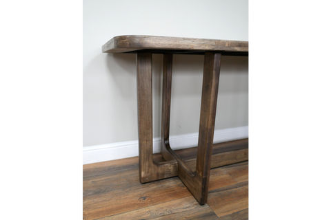Wooden dining table with rectangular top and sturdy square legs, angled close-up view on wooden floor.