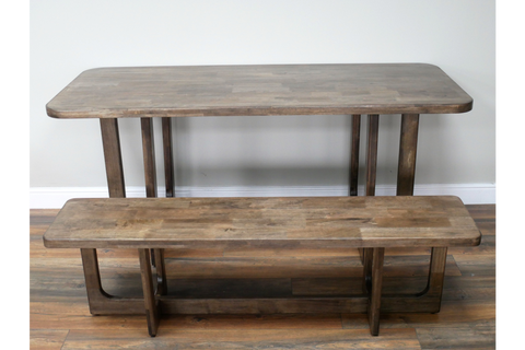 Rectangular wooden dining table with matching bench, natural brown finish, front angle on wooden floor.