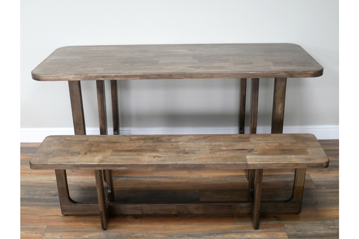 Rectangular wooden dining table with matching bench, natural brown finish, front angle on wooden floor.