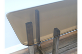 Rectangular dining table with tinted glass top and wooden legs, shown from a top corner angle.