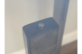 Close-up detail of dark wooden leg with black adjustable foot under clear glass tabletop viewed at an angle.