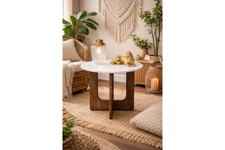 Round marble top side table with dark wooden base, shown in warm boho living room setting, front angle.
