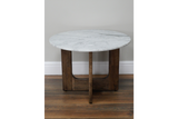 Round marble top side table with dark wood base, front view on wooden floor and light gray wall background.