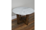 Round side table with white marble top and dark wooden legs on wooden floor, angled view.