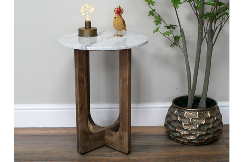 Small round side table with white marble top and dark wooden legs, shown from front angle with decor on top.