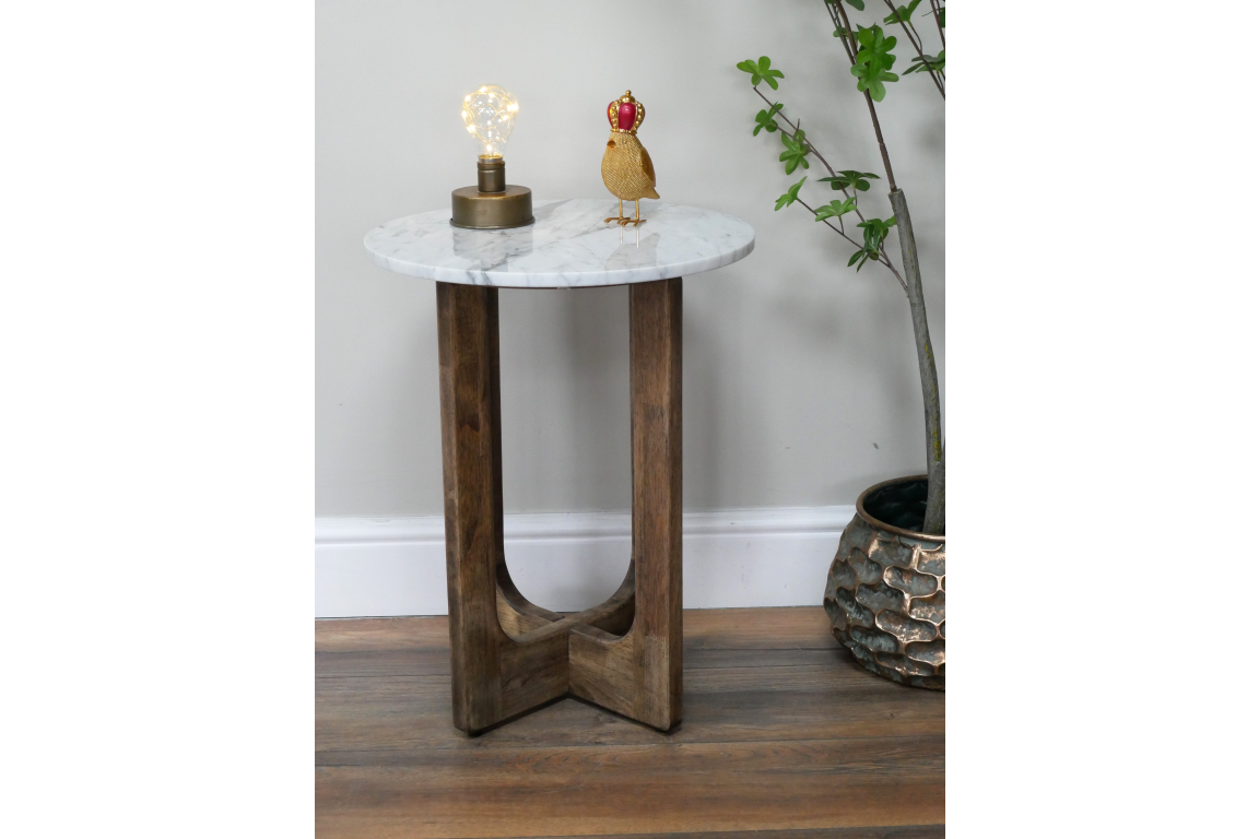 Small side table with round white marble top and dark wooden crossed legs, shown with lamp and decorative bird on top.