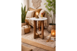 Small side table with round white marble top and dark wood U-shaped legs in cozy living room corner.