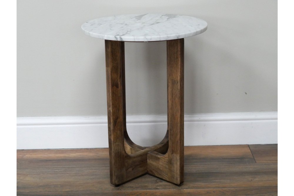 Small round side table with white marble top and dark brown wooden legs, shown from front angle on wood floor.