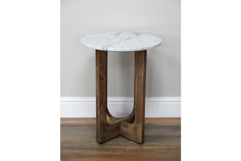 Small round side table with white marble top and wooden interlocking legs, shown front on against a wall.