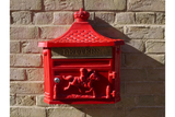 Red cast iron wall-mounted post box with horse design on brick wall