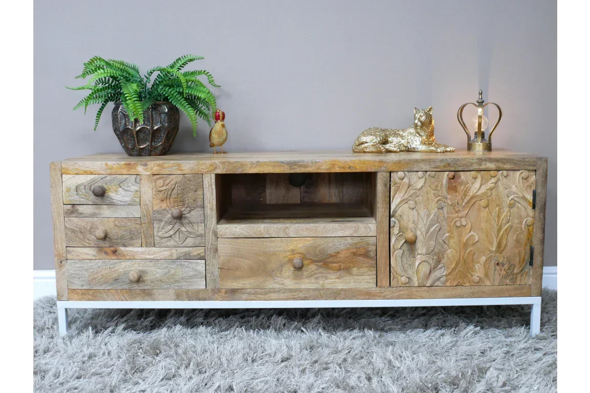 Mango wood TV unit with carved details, brass handles, open shelf and drawers, on white legs