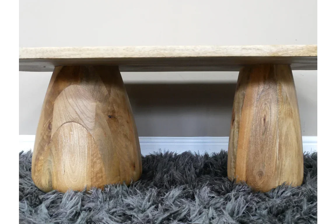 Solid wood coffee table base with two rounded legs on thick grey rug