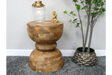 Round wood side table with decorative lamp and gold ornament beside potted plant