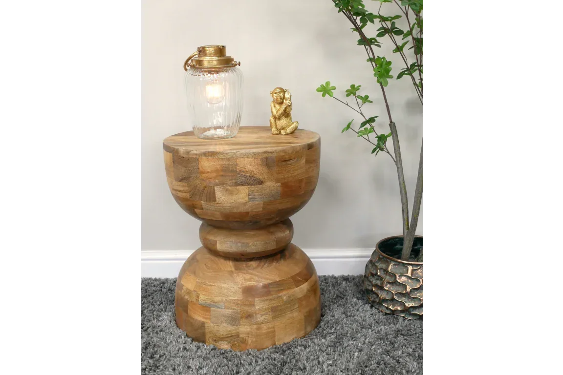 Solid wood side table with rounded base, lamp, gold ornament, grey rug and indoor plant