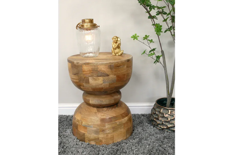 Solid wood side table with rounded base, lamp, gold ornament, grey rug and indoor plant