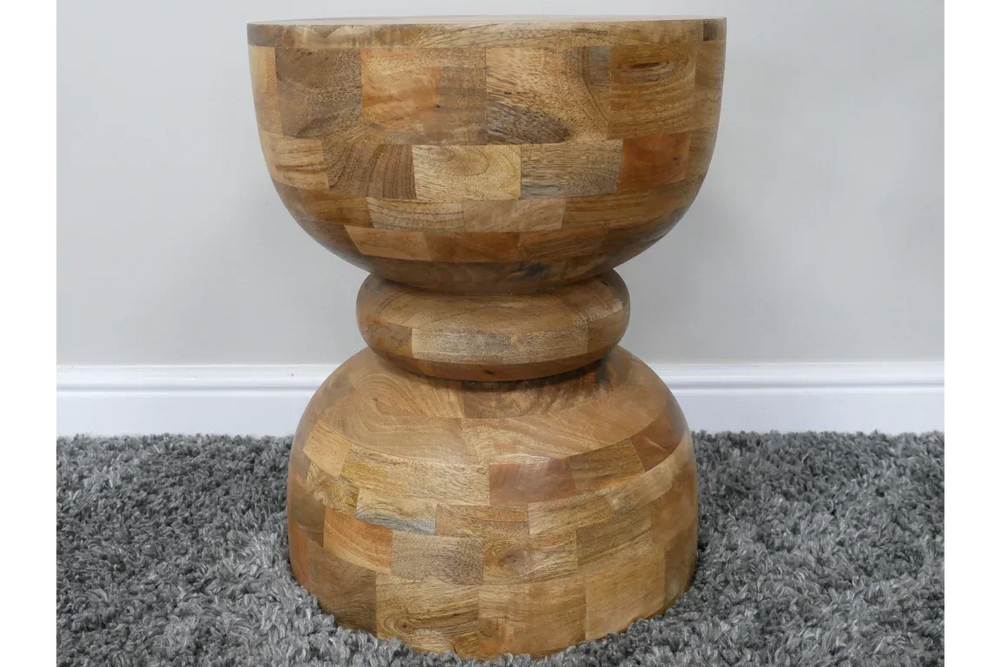 Solid wood side table with geometric hourglass shape on grey carpet
