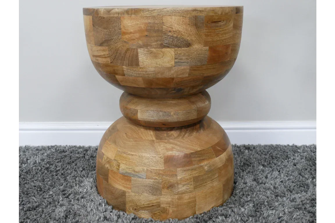 Solid wood side table with geometric hourglass shape on grey carpet