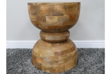 Solid wood side table with geometric hourglass shape on grey carpet