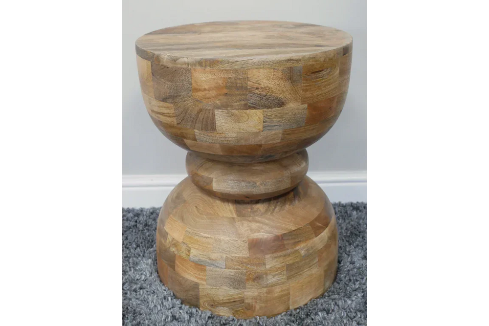 Round solid wood side table with natural finish on grey carpet