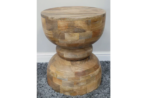 Round solid wood side table with natural finish on grey carpet